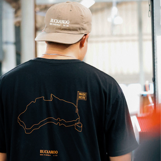 Person wearing a black t-shirt with a map design and 'Buckaroo' branding, standing indoors.