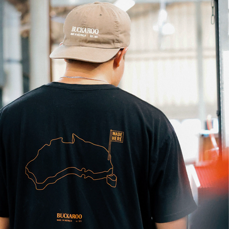 Person wearing a black t-shirt with a map design and 'Buckaroo' branding, standing indoors.
